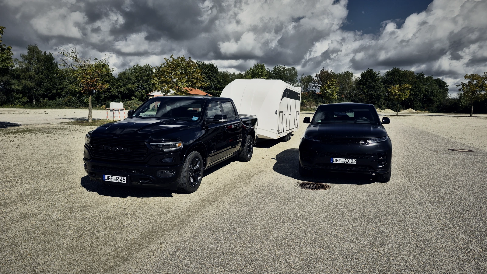 Beide Zugfahrzeuge nebeneinander: RAM mit geschlossenem Anhänger und Range Rover Sport