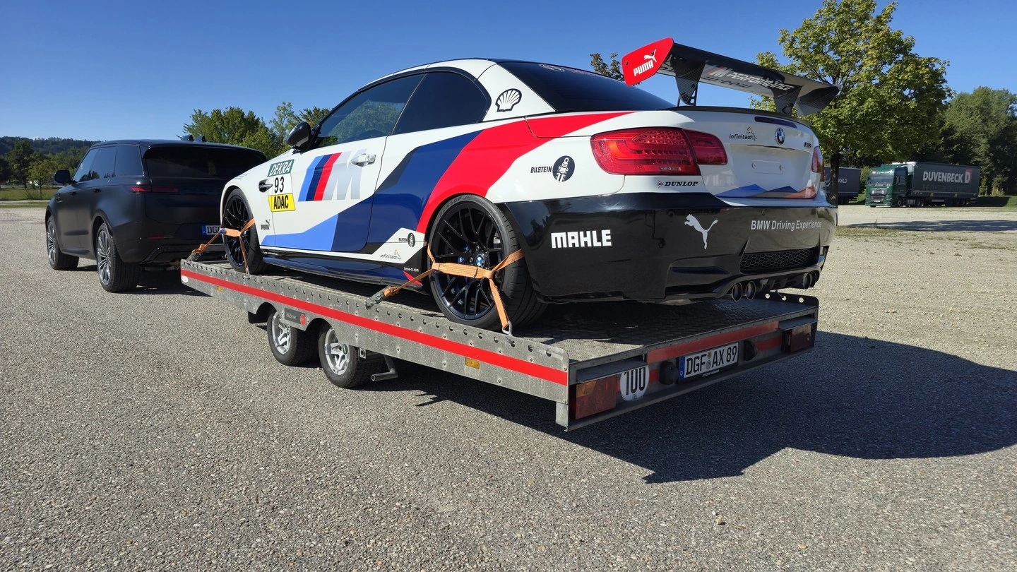 BMW M3 Rennwagen mit Heckflügel, verzurrt auf der offenen Plattform