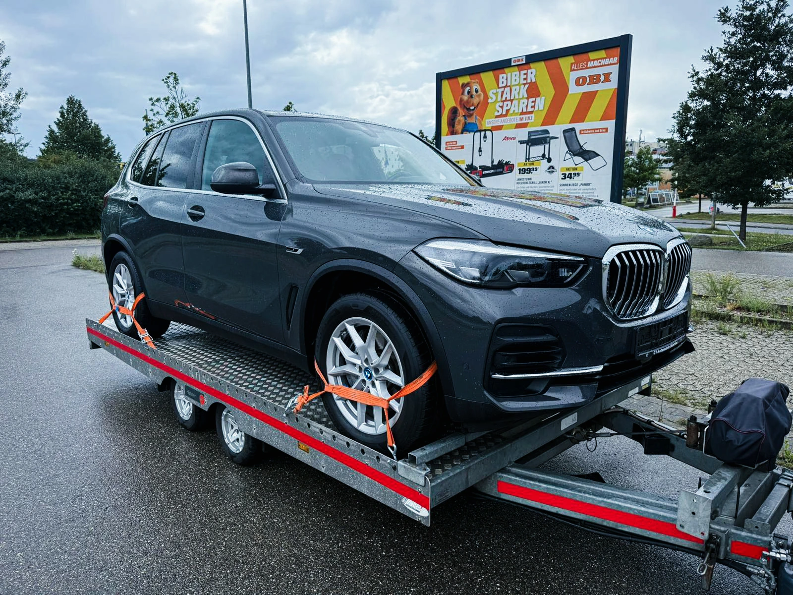 BMW X5 auf der offenen Plattform, mit orangefarbenen Radgurten gesichert